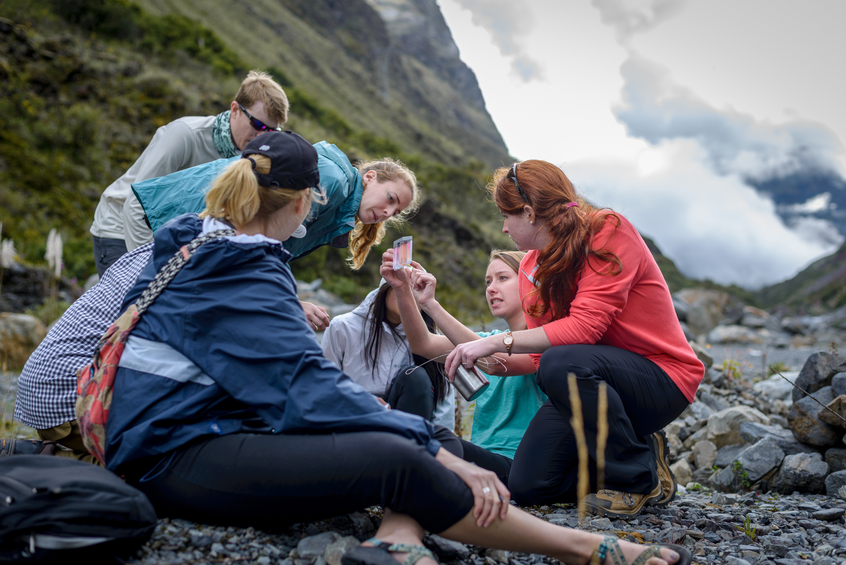A group of students by a mountain looks at a water quality test