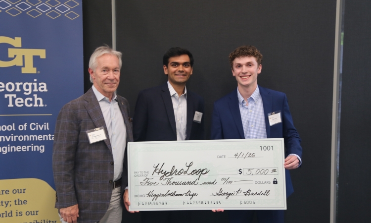 Bill Higginbotham presents a check to Anuj Patel, center, and Robbie Hauf of winning team HydroLoop