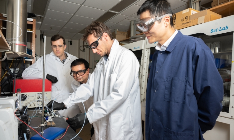 Four men wearing protective equipment working in a laboratory