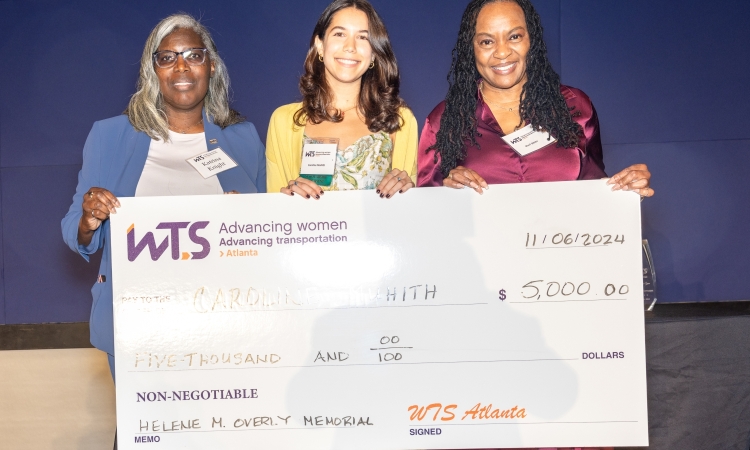 Caroline Muhith, center, receiving a large ceremonial check from WTS members Katrina Knight, left, and Sheri White, right, at the Georgia Aquarium on November 6, 2024.