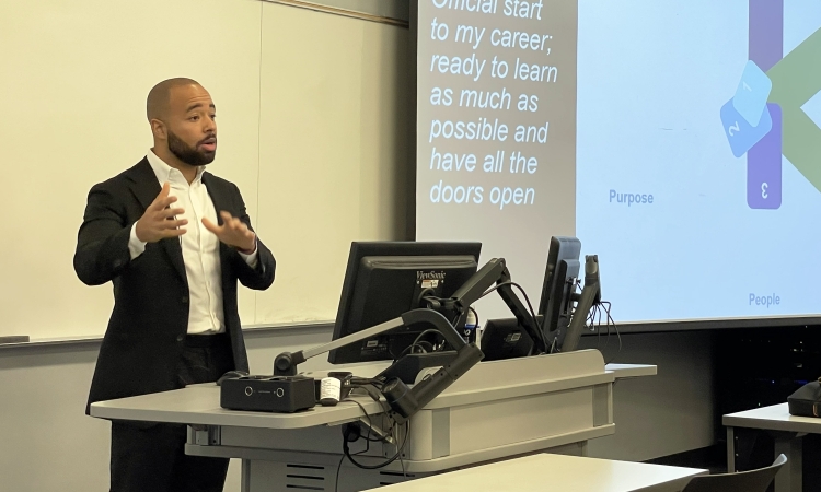 Jacob Tzegaegbe speaks in front of a projector screen