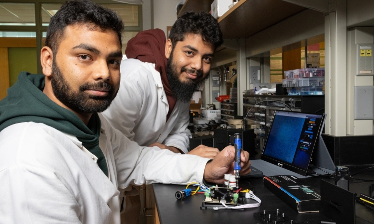 two men in lab coats working with an electronic device 