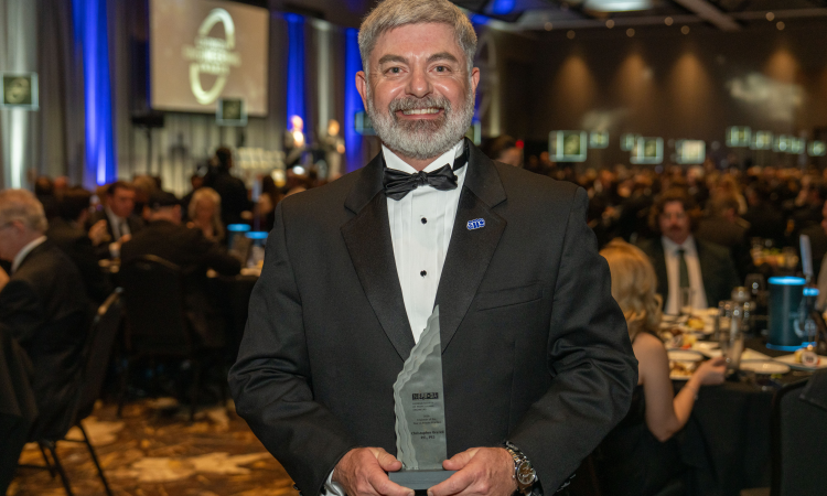 A man in a tuxedo holds an award 