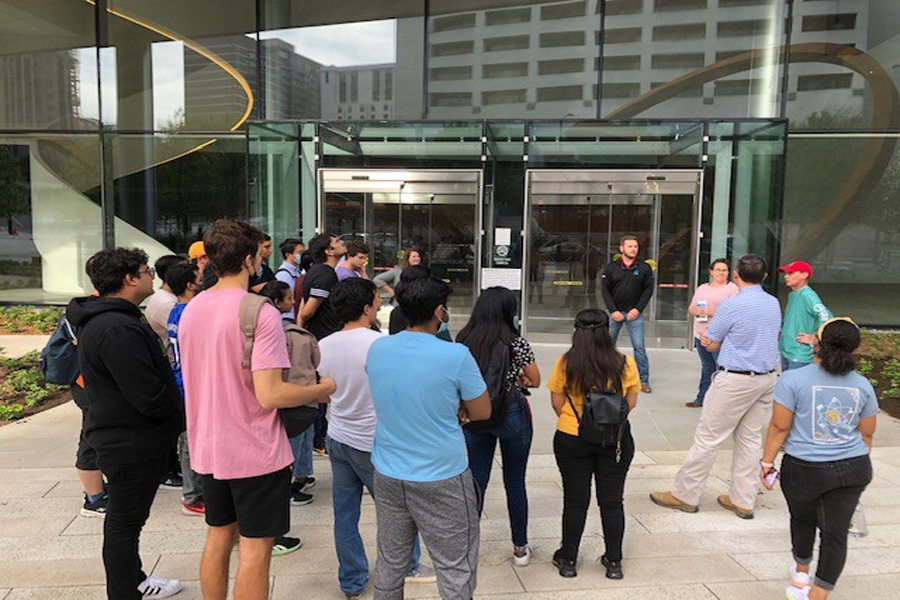 students visit the construction site of a glass front building