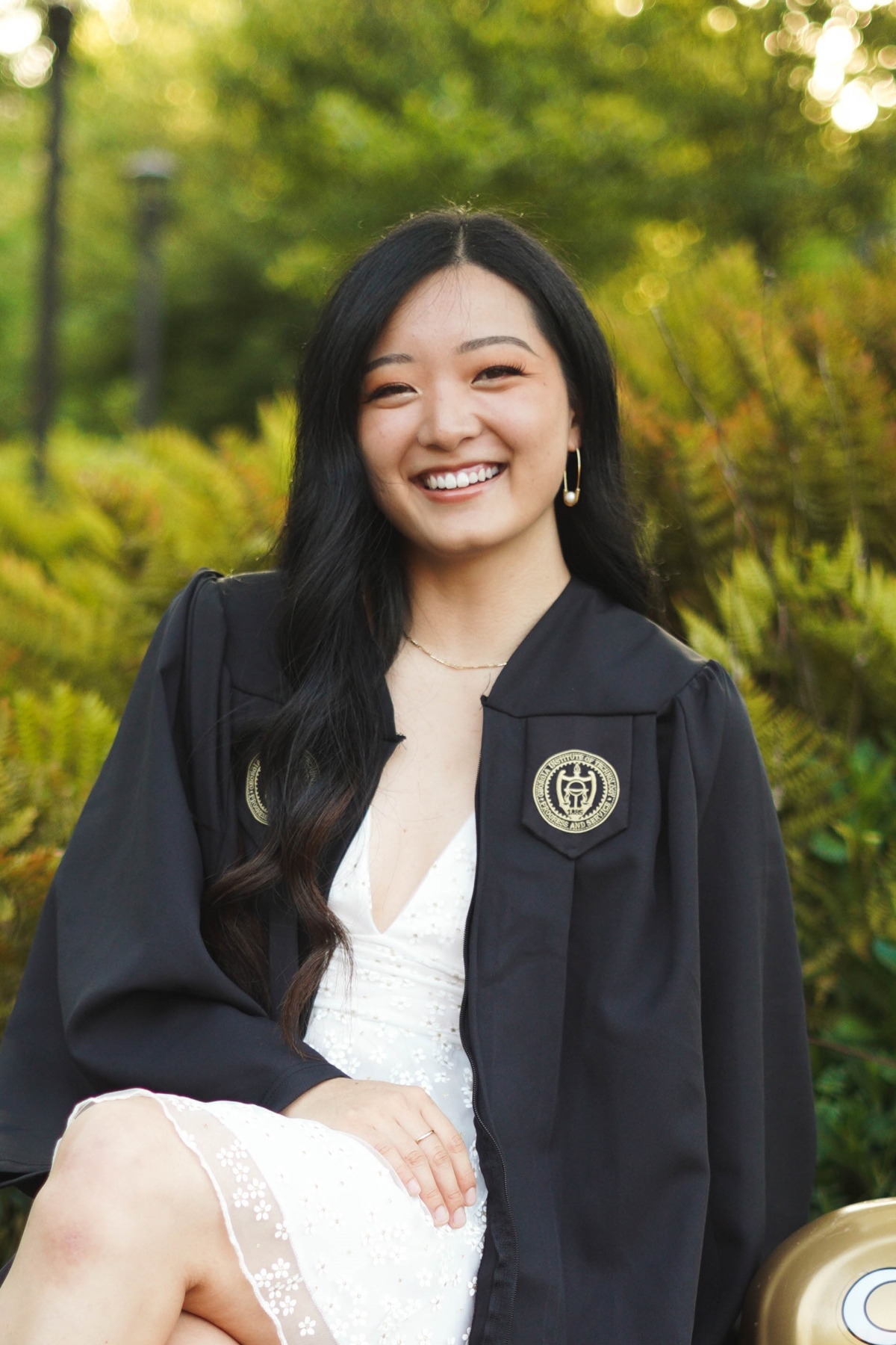 Woman sitting on car in graduation robe