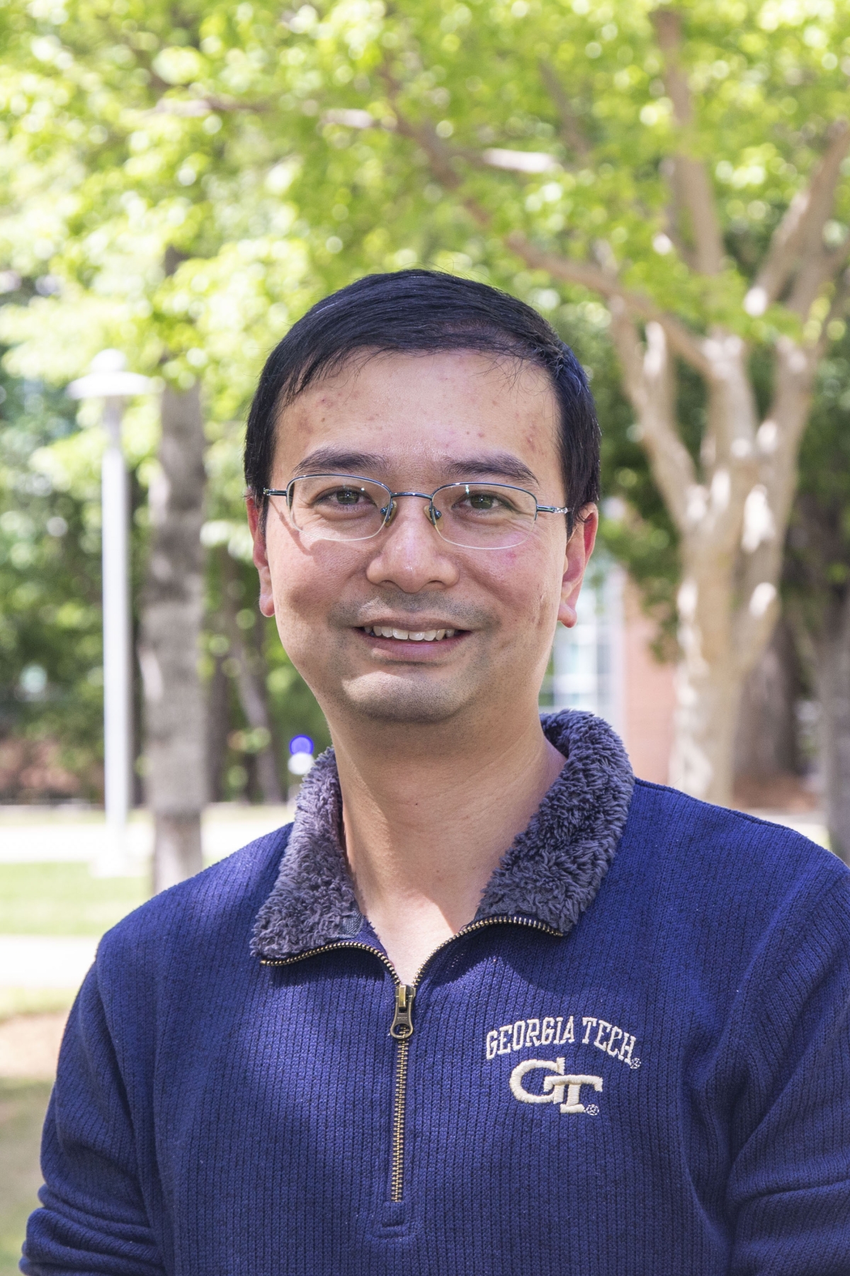 Man in glasses in front of trees