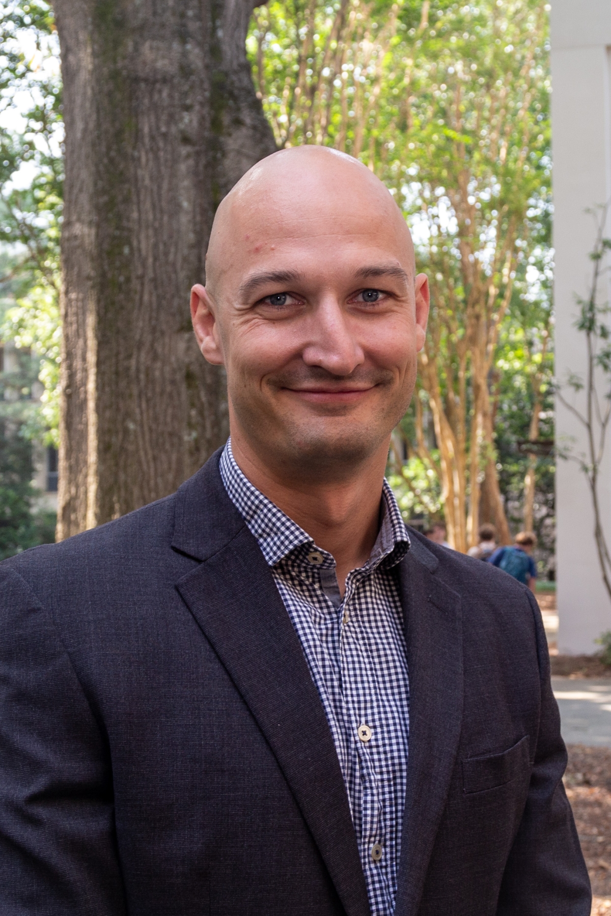 Headshot of a man in a patterned shirt and navy blazer