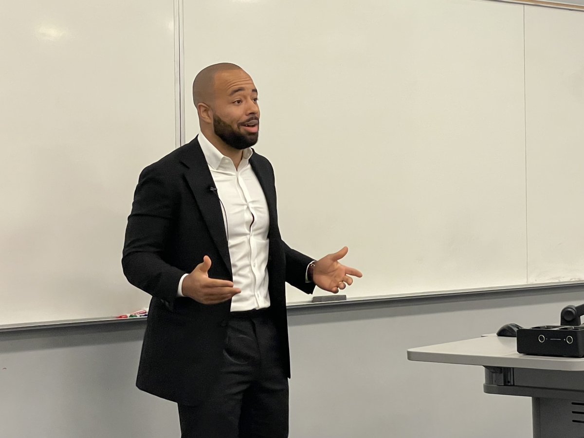 Jacob Tzegaegbe speaking in front of a white board