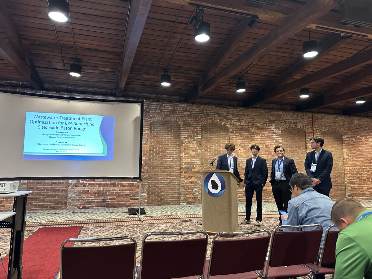 Four men present at a podium