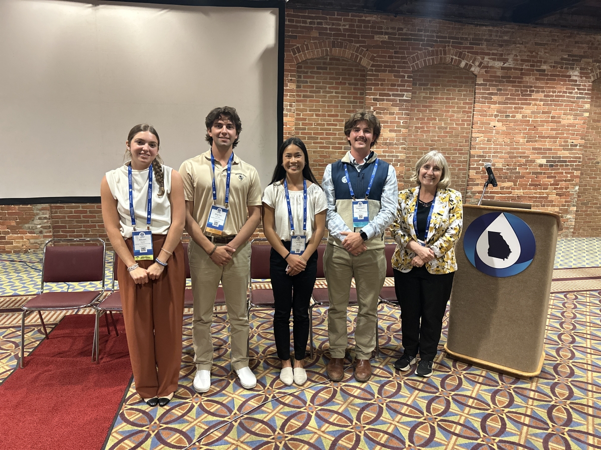 Five people pose next to a podium 