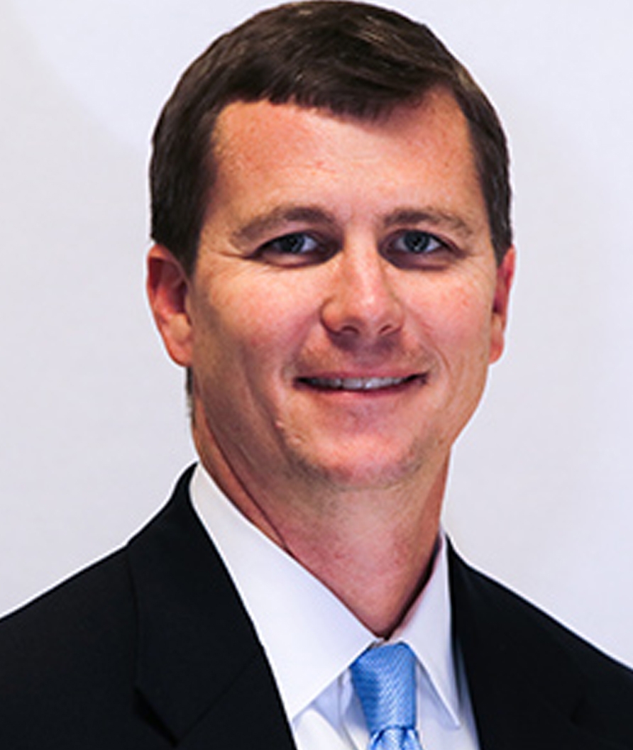 Portrait of Scott Johnson in a navy blue blazer with a white dress shirt and light blue tie