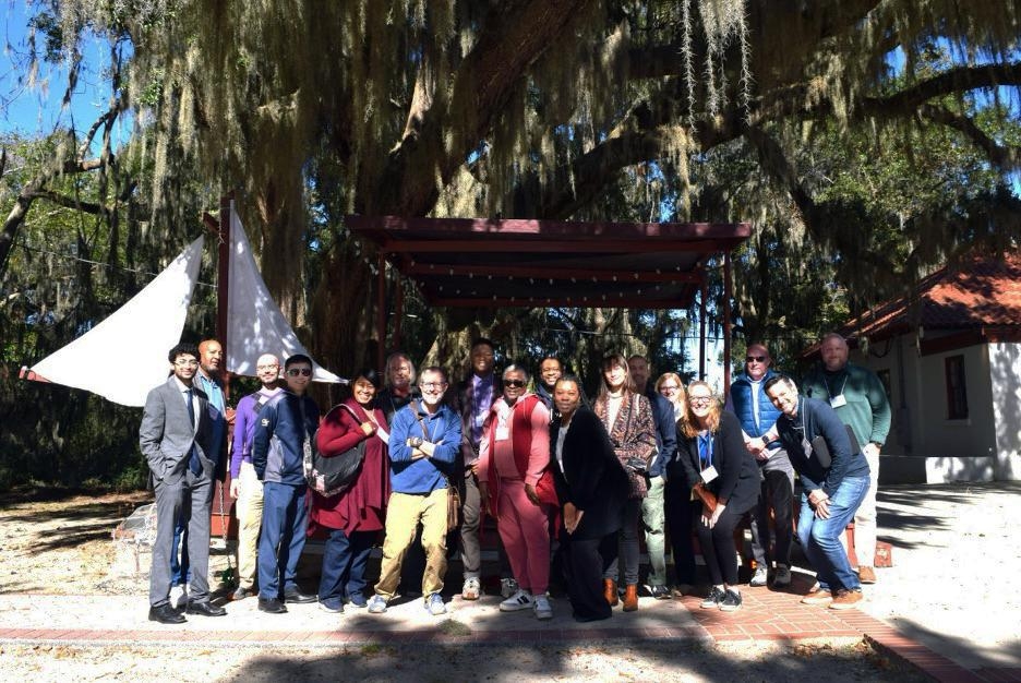 A group of people standing in front of a live oak tree