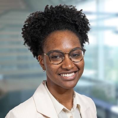 Portrait of Lauren Otober wearing glasses and a cream-colored blazer and blouse