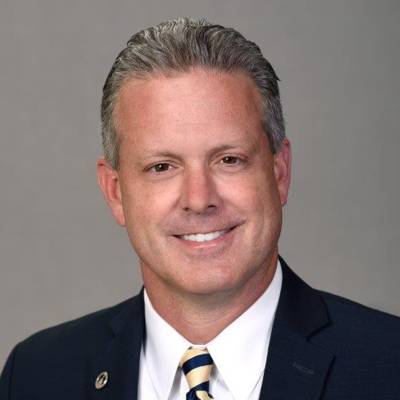 Chuck Warbington in a blue suit, white shirt and gold and blue tie